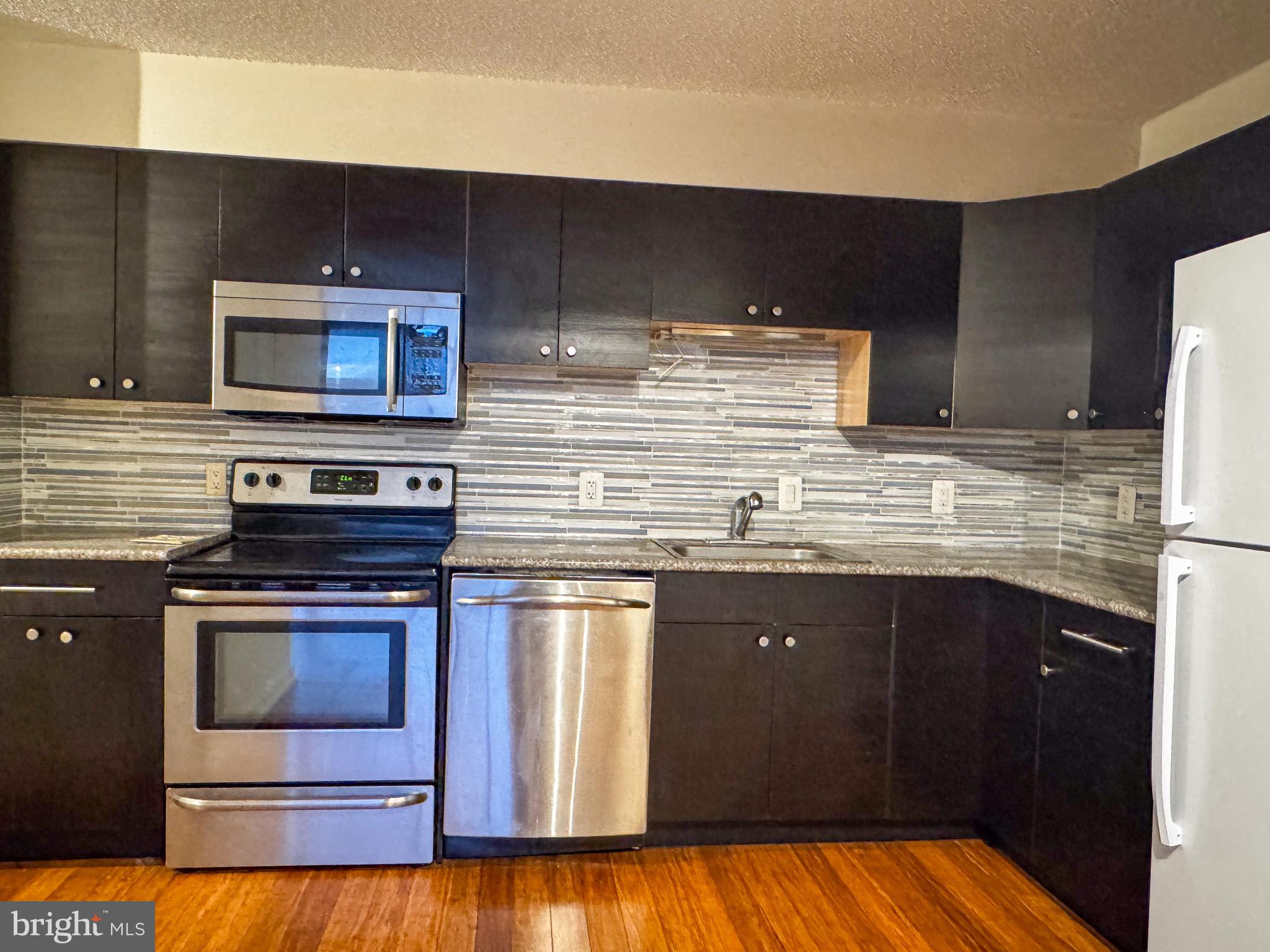 2141 P Street Northwest, Unit 705 Washington, DC 20037 - Photo 3 of 22 a kitchen with stainless steel appliances wooden cabinets and a stove top oven