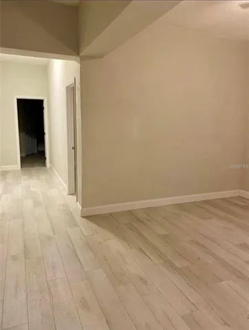 a view of a hallway with wooden floor and a bathroom