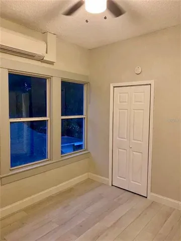a view of empty room with wooden floor and kitchen
