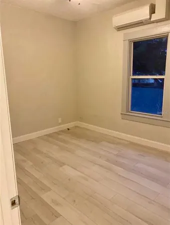 an empty room with a chandelier fan and wooden floor