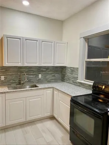 a kitchen with granite countertop white cabinets and stainless steel appliances