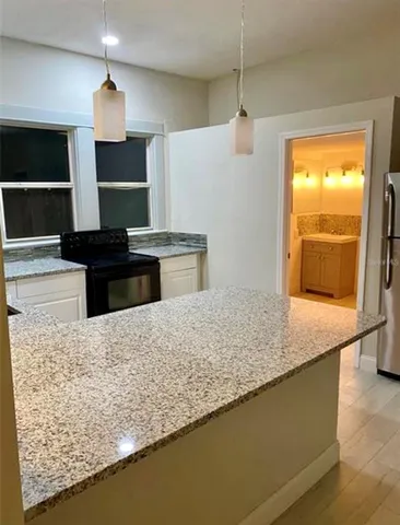 a kitchen with granite countertop a sink a counter top space appliances and cabinets