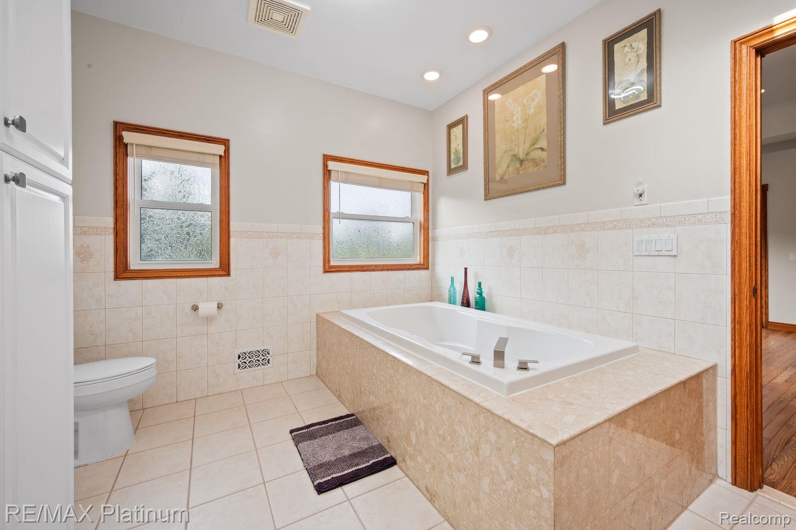 8922 McClements Road Brighton, MI 48114 - Photo 18 of 65 Soaking tub with a tiled surround, recessed lighting, and dual windows with wood trim