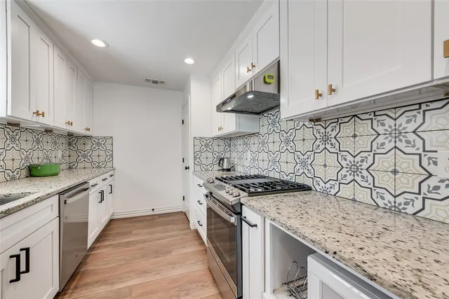 a kitchen with stainless steel appliances granite countertop a sink and a stove