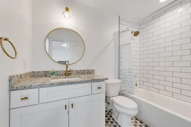 a bathroom with a granite countertop toilet sink and mirror