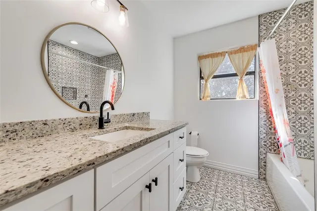 a bathroom with a granite countertop sink a toilet and a mirror