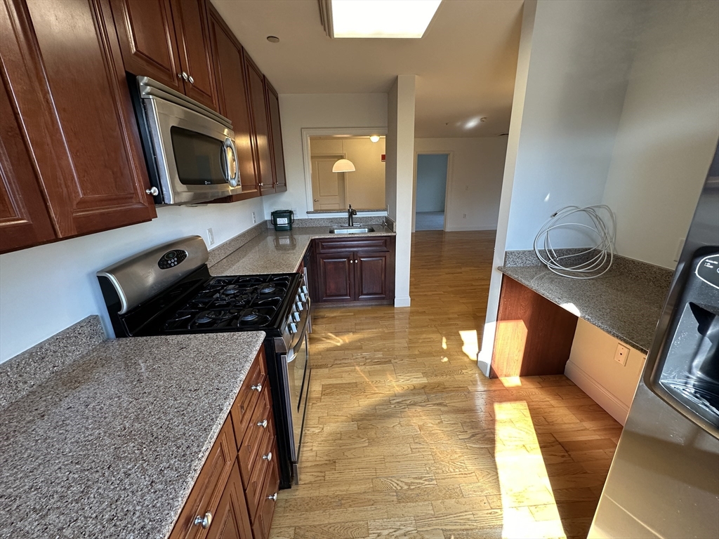 318 Rindge Avenue, Unit 216 Cambridge, MA 02140 - Photo 6 of 15 a kitchen with a stove a sink and a microwave