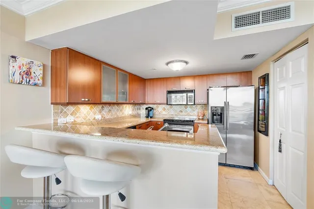 a kitchen with stainless steel appliances granite countertop a refrigerator a sink a stove and island