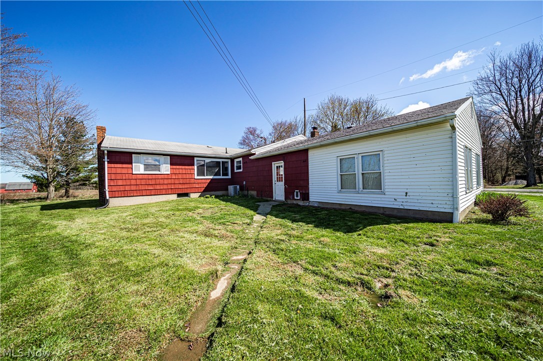 3395 Maple Road Jefferson, OH 44047 - Photo 16 of 36 Back of property with central air condition unit and a lawn