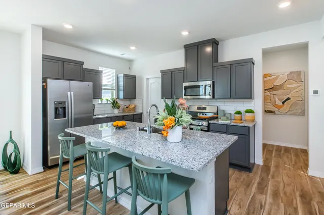 a kitchen with stainless steel appliances granite countertop a table chairs refrigerator and microwave