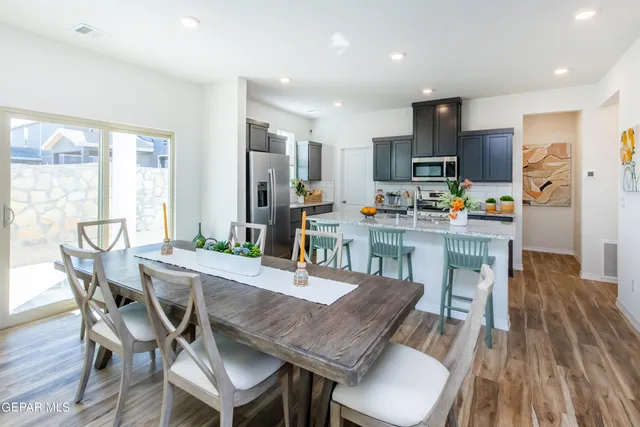 a dining room with stainless steel appliances a dining table chairs and wooden floor