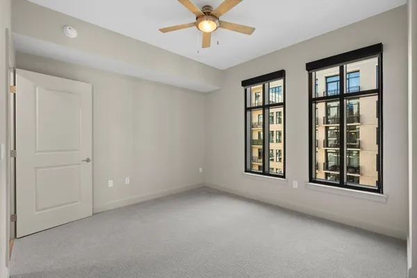 an empty room with windows and fan