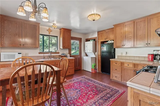 a kitchen with stainless steel appliances granite countertop a refrigerator a stove a sink dishwasher and wooden cabinets with wooden floor