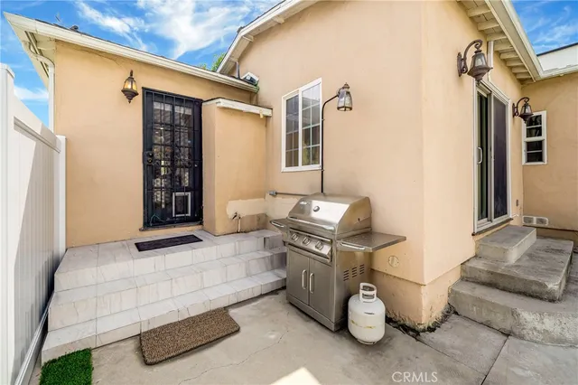 a view of a patio with table and chairs and barbeque grill with floor to ceiling window
