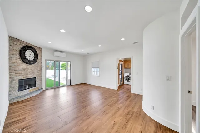 a view of an empty room with wooden floor fireplace and a window