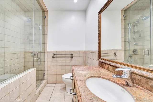 a bathroom with a granite countertop bathtub sink vanity mirror and toilet