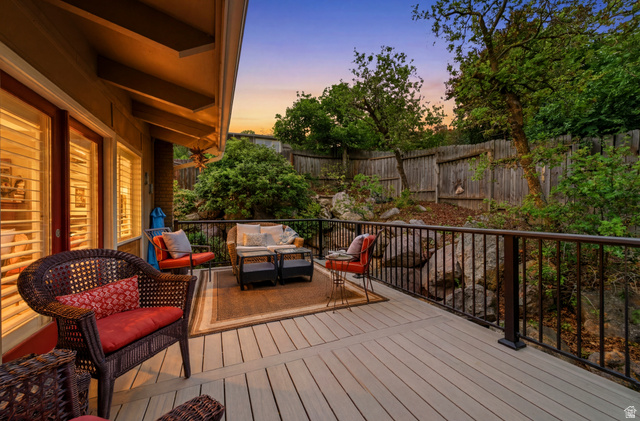 3674 Oak Rim Way Salt Lake City, UT 84109 - Photo 3 of 47 Spacious outdoor deck featuring wood-finish flooring, dark metal railings, and a sloped, treed landscape