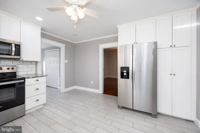 a large kitchen with granite countertop a stove top oven a sink dishwasher and a refrigerator with wooden floor