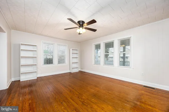 a view of empty room with wooden floor and ceiling fan