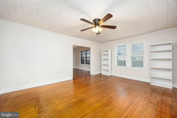 a view of an empty room with window and wooden floor