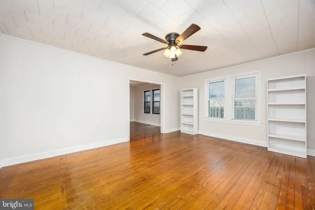 a view of an empty room with window and wooden floor