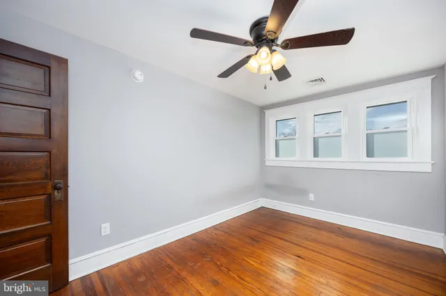 an empty room with wooden floor closet and windows