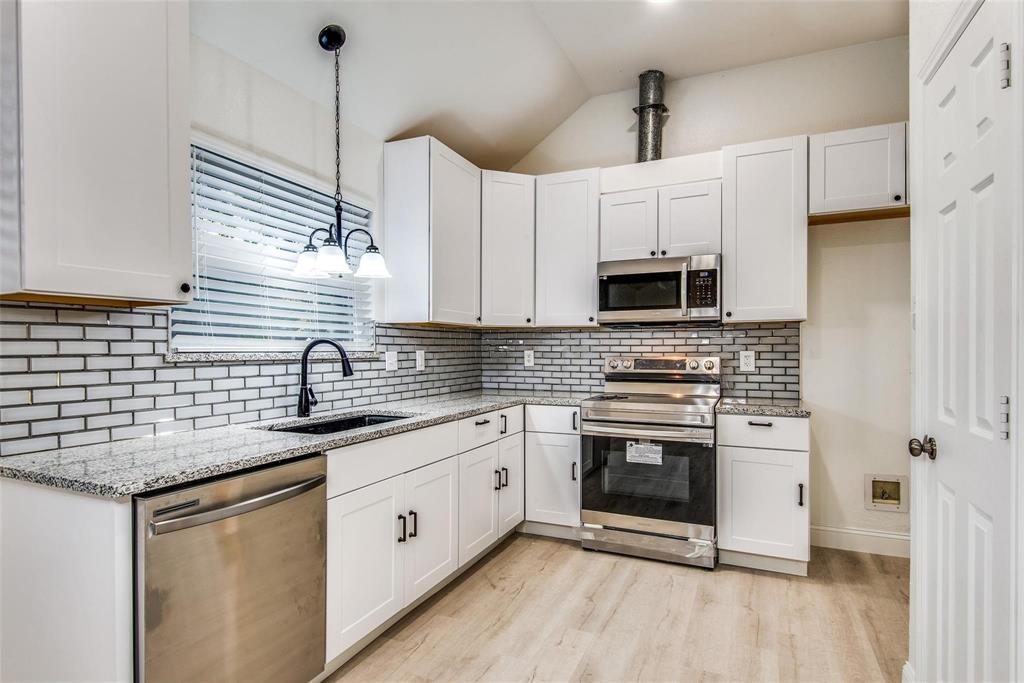 2504 Whetstone Drive Corinth, TX 76210 - Photo 10 of 19 a kitchen with granite countertop a sink stainless steel appliances and white cabinets