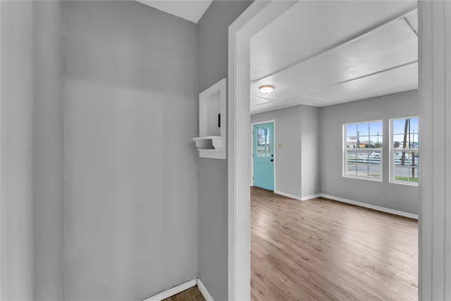 a view of an empty room with a window and wooden floor