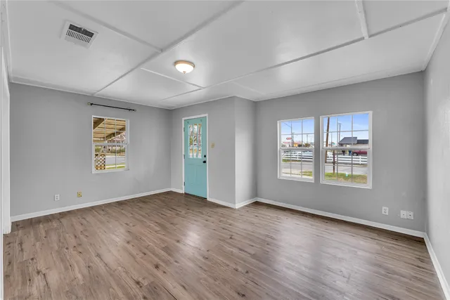 a view of an empty room with a window and wooden floor