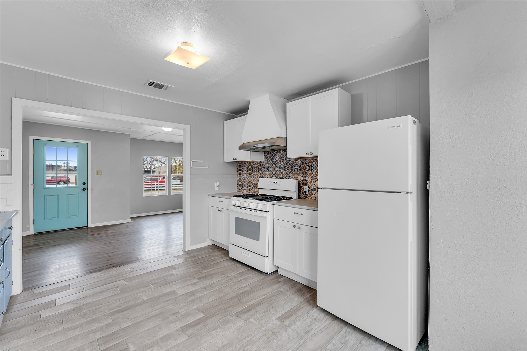 117 Travis Street Taylor, TX 76574 - Photo 7 of 23 a kitchen with refrigerator a stove cabinets and wooden floor