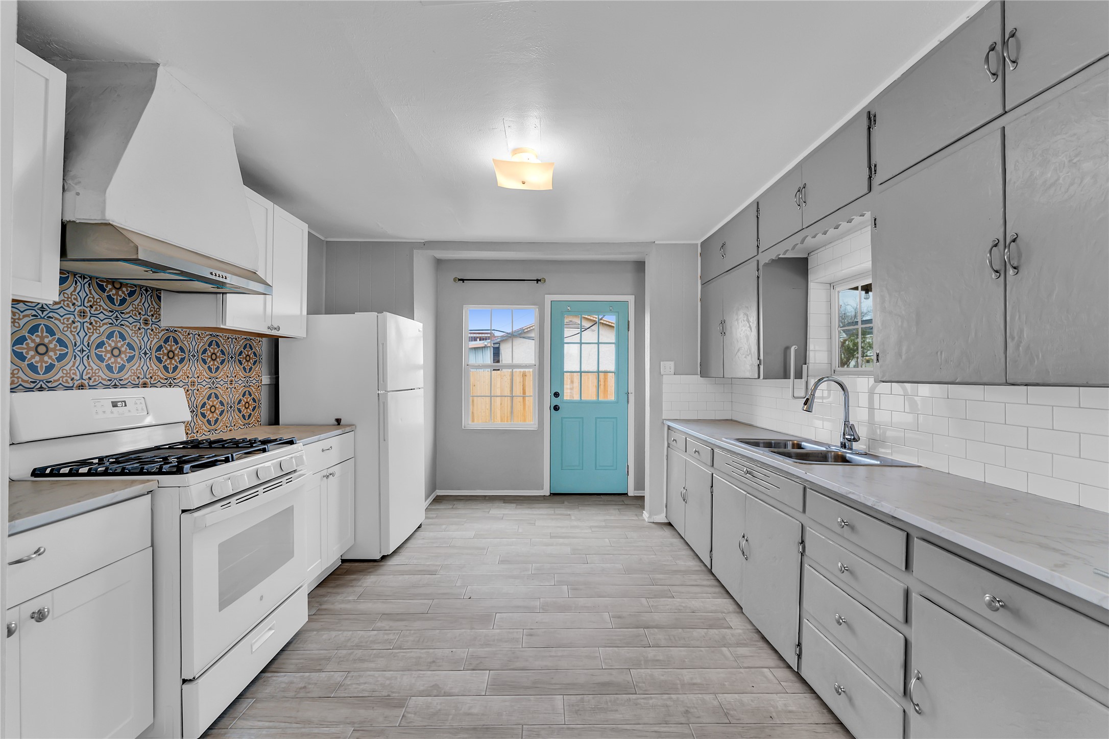 117 Travis Street Taylor, TX 76574 - Photo 8 of 23 a large white kitchen with stainless steel appliances granite countertop a stove a sink dishwasher and white cabinets with wooden floor