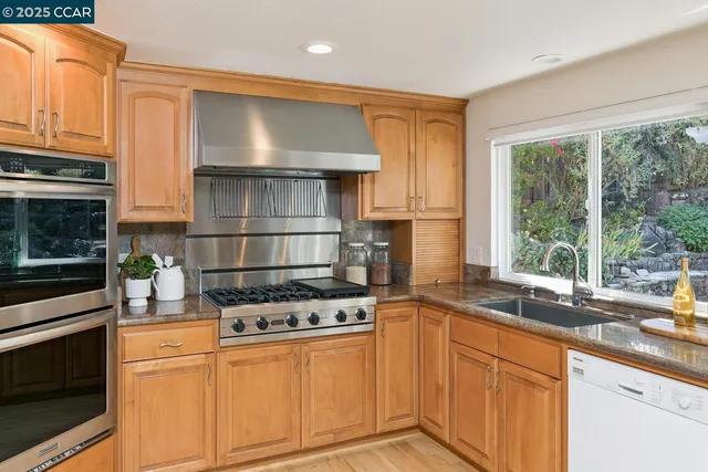 a kitchen with stainless steel appliances granite countertop a stove a sink and a microwave
