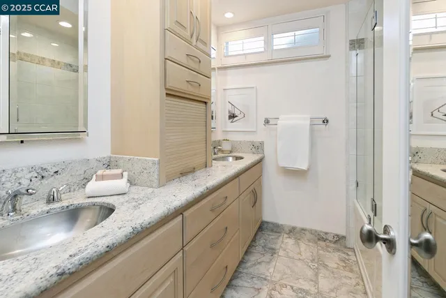 a bathroom with a granite countertop sink a mirror and a shower