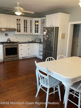 a kitchen with stainless steel appliances granite countertop a stove a refrigerator a sink a dining table and chairs