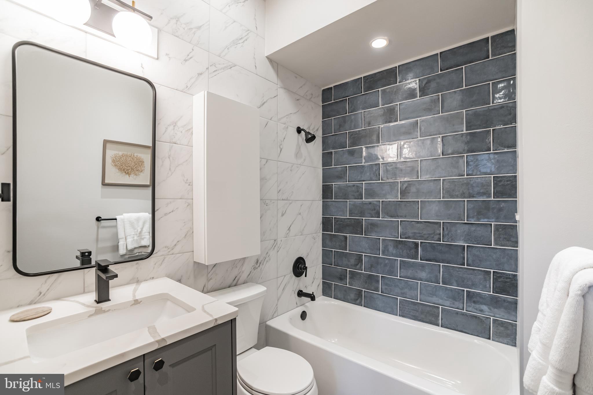 1238 Callowhill Street, Unit 101 Philadelphia, PA 19123 - Photo 13 of 17 a bathroom with a granite countertop bathtub sink vanity mirror and toilet