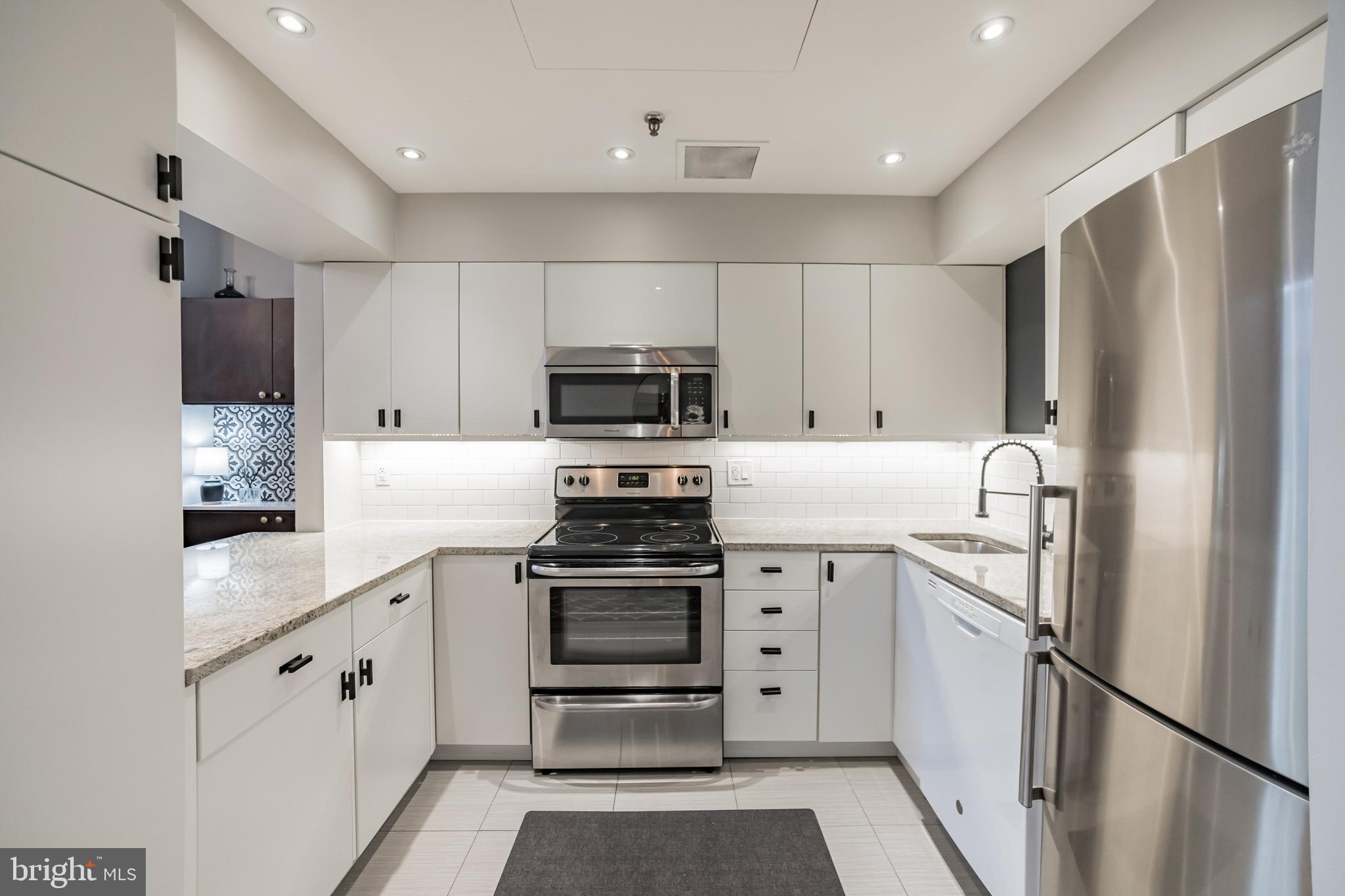 1238 Callowhill Street, Unit 101 Philadelphia, PA 19123 - Photo 6 of 17 a kitchen with white cabinets and stainless steel appliances
