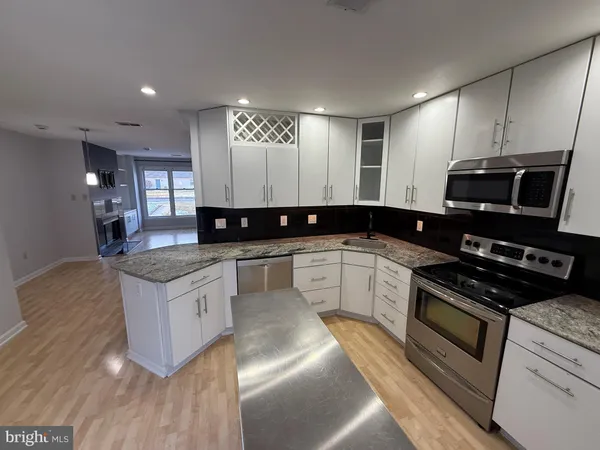 a kitchen with stainless steel appliances granite countertop a stove a sink and a microwave