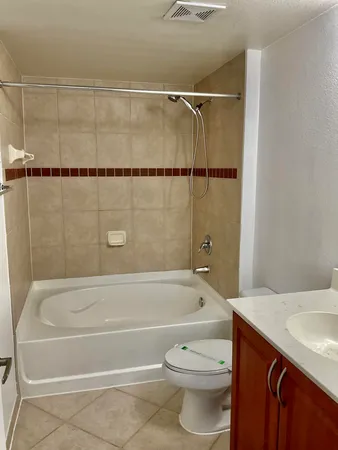 a bathroom with a granite countertop bathtub shower and toilet