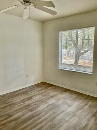 an empty room with wooden floor and windows