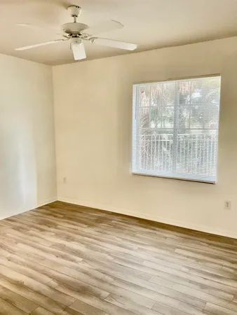 a view of an empty room with a window and wooden floor