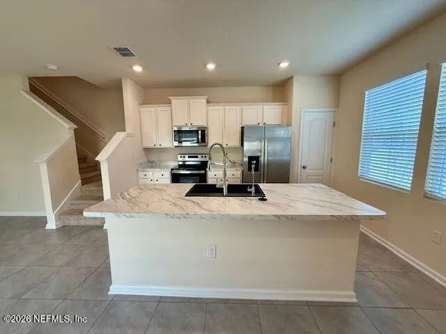 a kitchen with kitchen island a stove a sink a refrigerator and cabinets