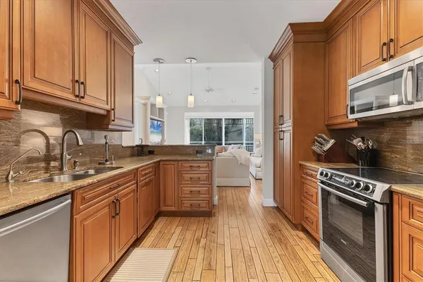 a kitchen with stainless steel appliances a stove a sink cabinets and a wooden floor
