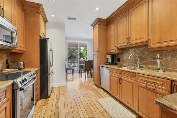 a kitchen with stainless steel appliances granite countertop a stove a sink dishwasher and a refrigerator with wooden floor