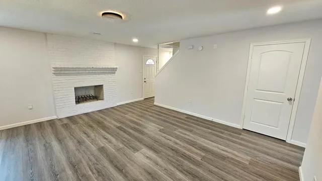 a view of empty room with wooden floor and fireplace
