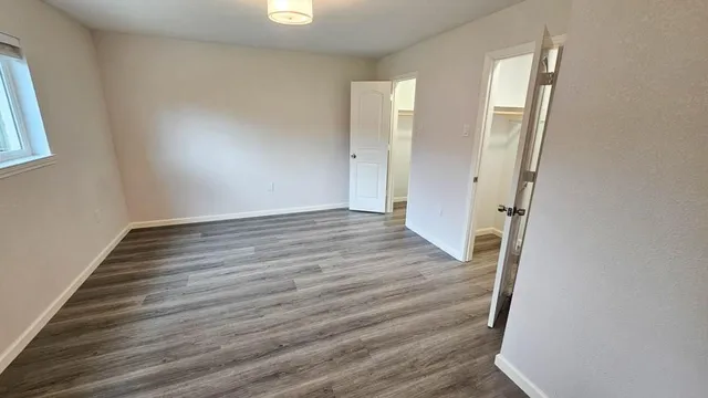an empty room with wooden floor and windows