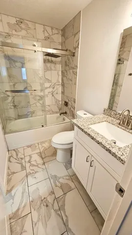 a bathroom with a granite countertop sink a toilet and shower