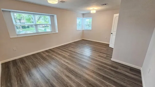 an empty room with wooden floor and windows