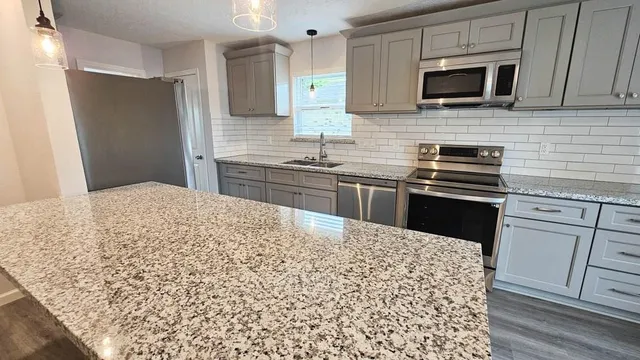 a kitchen with stainless steel appliances kitchen island granite countertop a sink stove and refrigerator