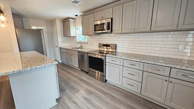 a kitchen with granite countertop cabinets stainless steel appliances and a sink