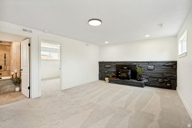 62 South Clark Lane Elk Ridge, UT 84651 - Photo 20 of 30 Spacious flex/family room featuring light-toned carpet flooring and a prominent black stone fireplace with an integrated wood stove.